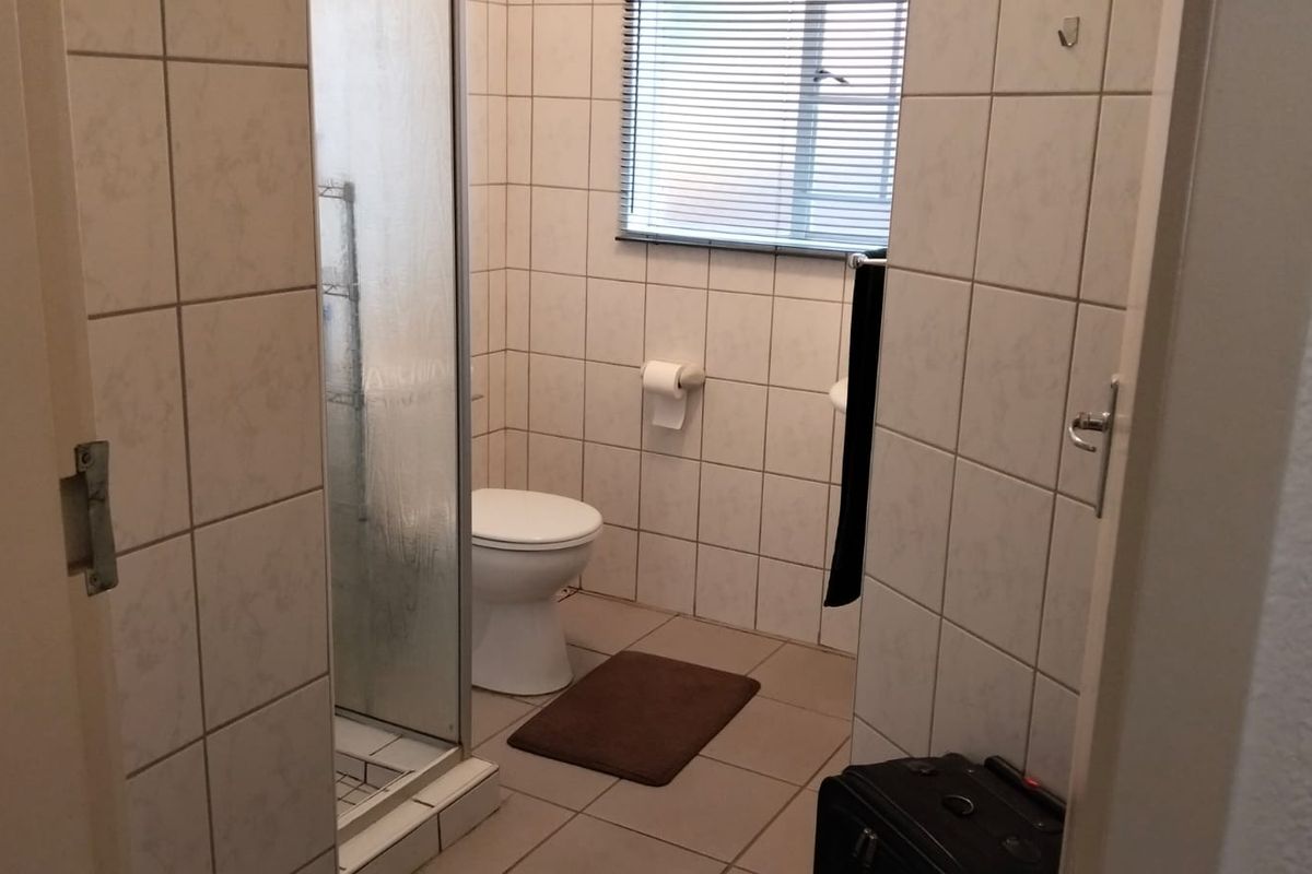 A functional bathroom featuring a shower enclosure, toilet, and tiled finishes throughout, providing a clean and practical space.