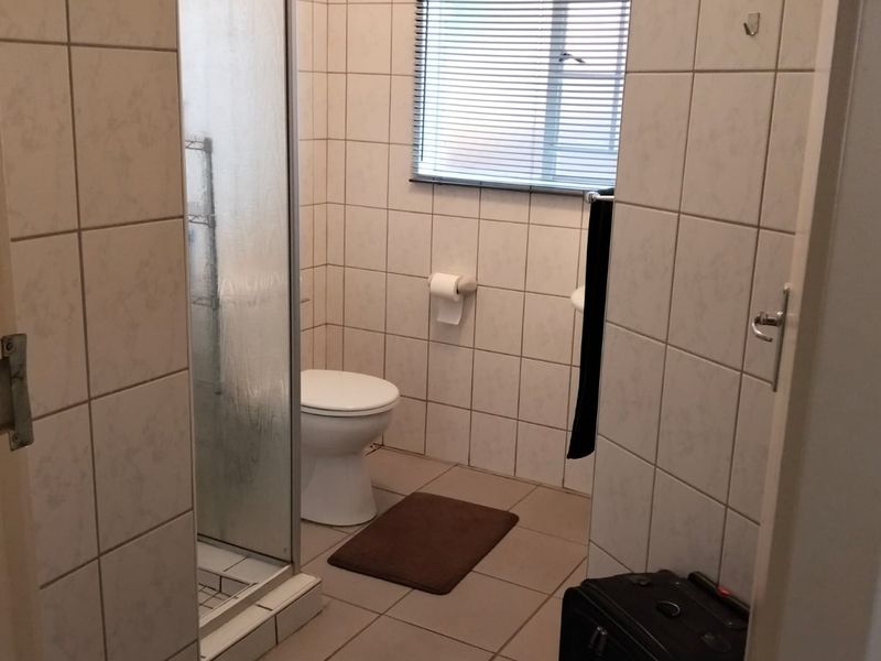 A functional bathroom featuring a shower enclosure, toilet, and tiled finishes throughout, providing a clean and practical space.