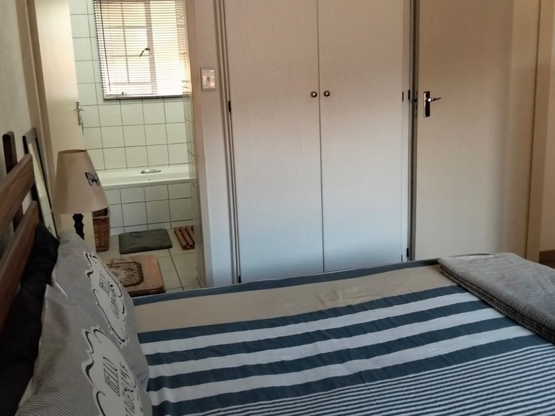 Bedroom featuring built-in cupboards and an adjoining en-suite bathroom with a bathtub.