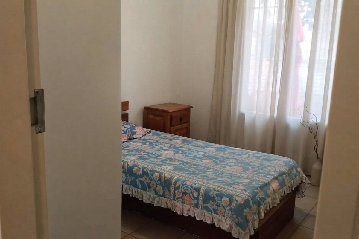 A bedroom featuring tiled flooring and window treatments, viewed from the doorway.