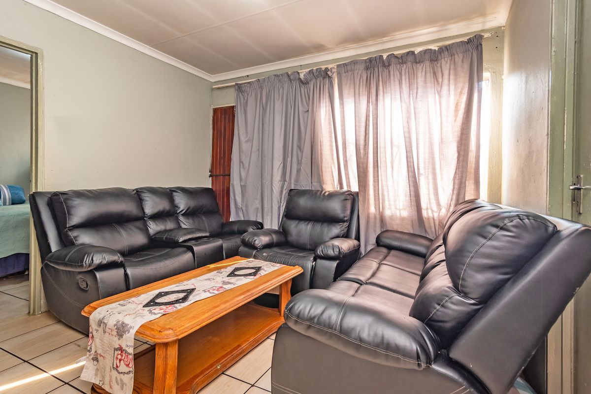 A living room featuring tiled flooring and coved ceilings, currently furnished with a seating arrangement.
