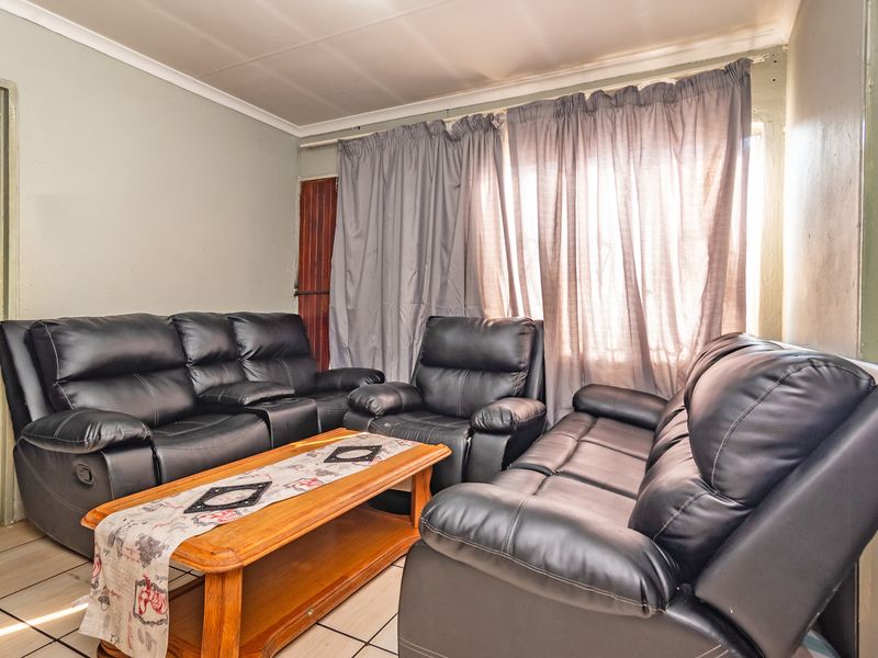 A living room featuring tiled flooring and coved ceilings, currently furnished with a seating arrangement.