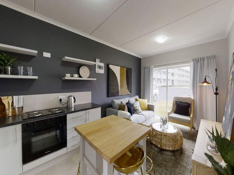 Modern open-plan living area featuring a compact kitchen with built-in oven, hob, and floating shelves, seamlessly connected to a bright lounge with sliding door access.