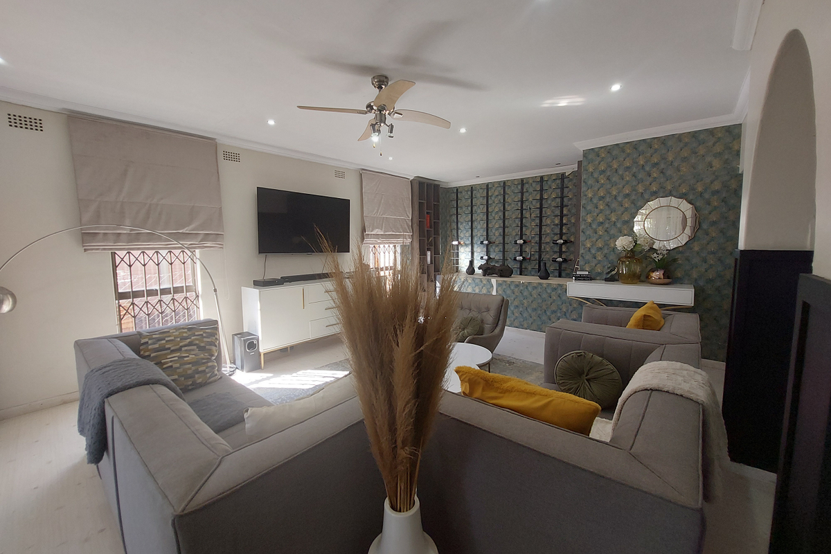 A well-maintained living room featuring a ceiling fan, recessed lighting, and a decorative built-in wine storage wall with patterned wallpaper.