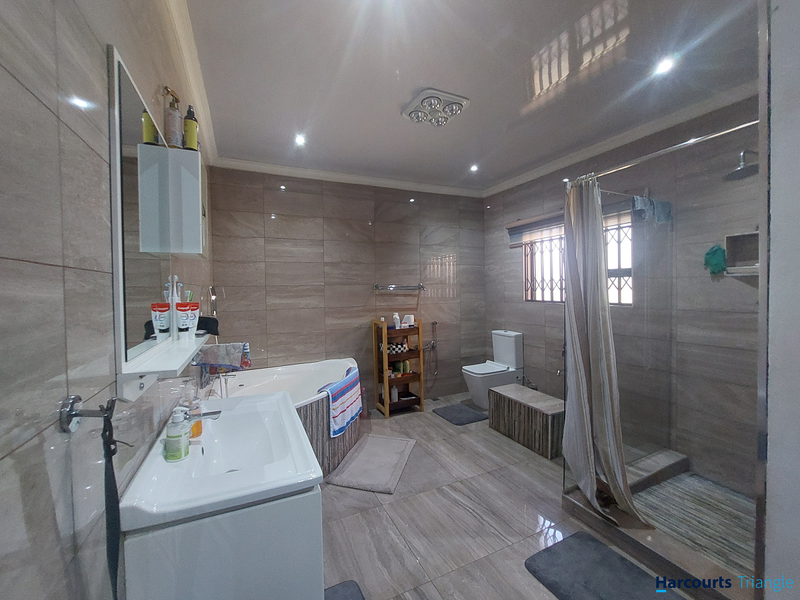 Modern bathroom featuring a corner bathtub, separate walk-in shower, wall-mounted toilet, and vanity basin with full-height wall tiling.