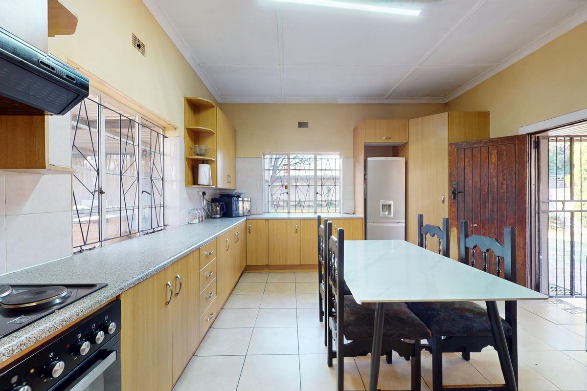 A functional kitchen featuring laminate cabinetry, built-in oven with hob, extractor fan, and tiled flooring, with direct access to the exterior.