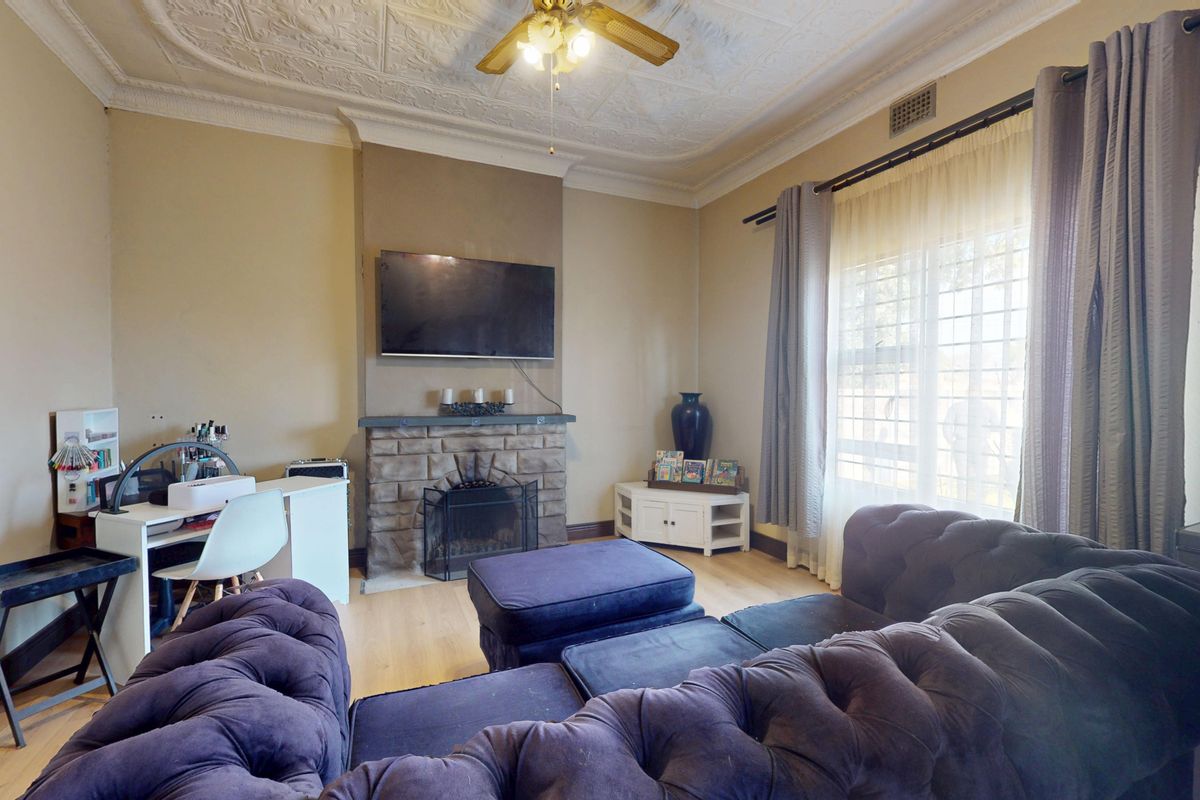 A living room featuring a stone fireplace, decorative ceiling rose, and cornice, providing a classic foundation for comfortable family living.