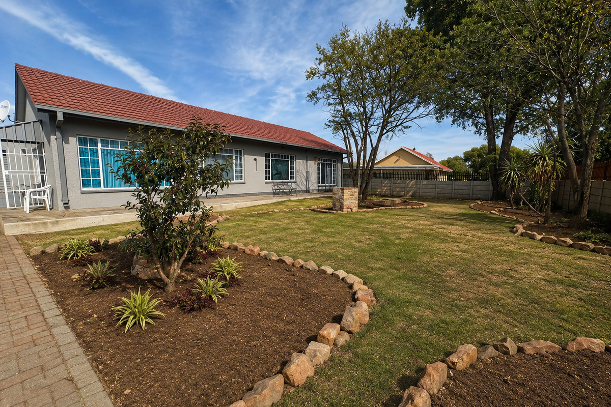 A well-maintained rear garden featuring a paved walkway, stone-edged garden beds, and a secure boundary wall, providing a pleasant outdoor space.