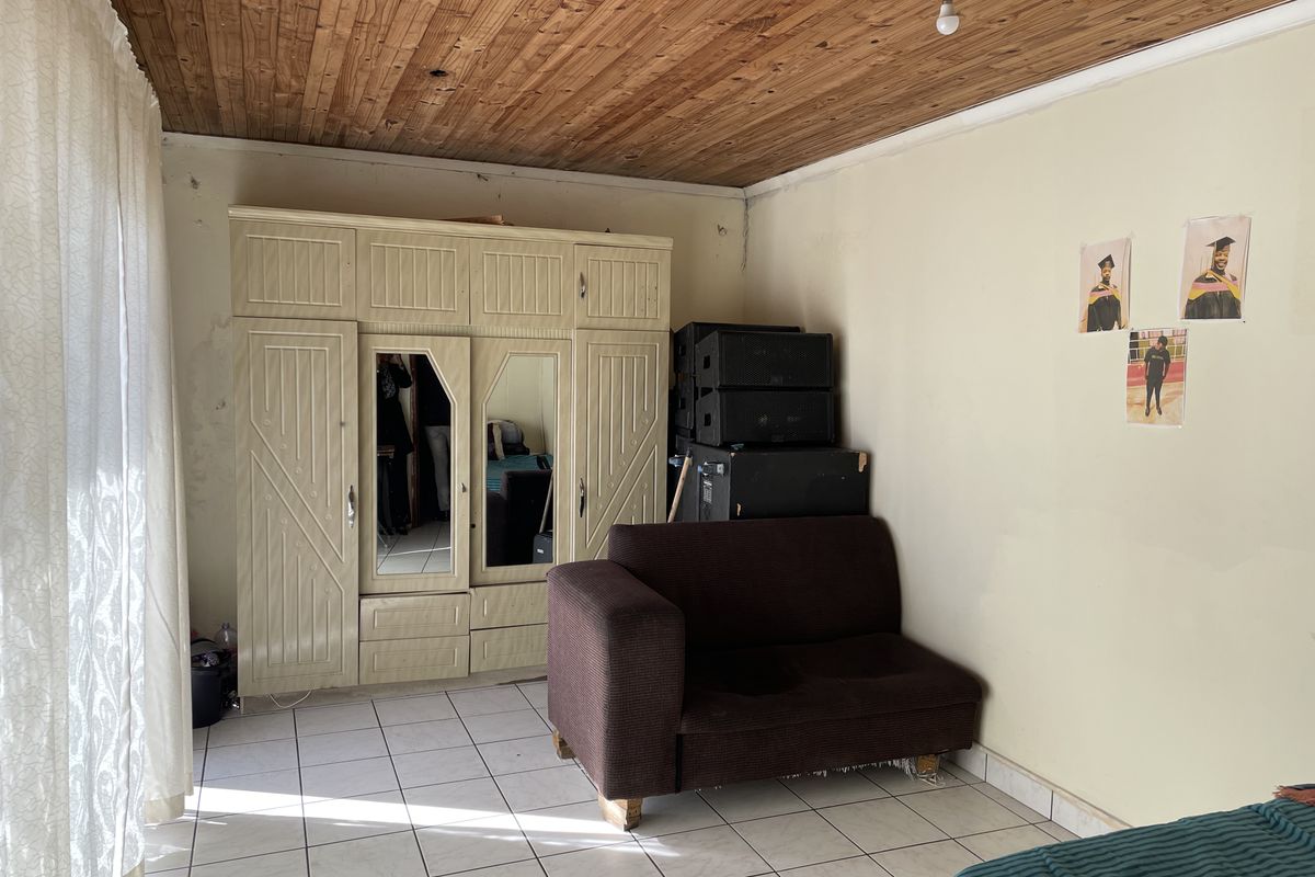 A bedroom featuring tiled flooring, a timber ceiling, and a built-in wardrobe, requiring cosmetic updates to the wall finishes.