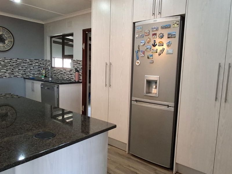 Modern kitchen featuring granite countertops, extensive built-in cabinetry, a mosaic tile backsplash, and integrated appliances in a functional layout.