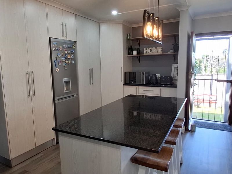 Modern kitchen featuring a central island with granite countertops, ample built-in cabinetry, and stylish pendant lighting, providing a functional and contemporary cooking space.