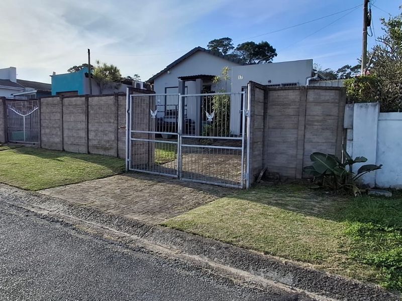 Front view of the property featuring a paved driveway, metal security gate, and precast concrete boundary wall.