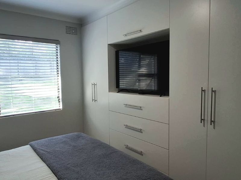A well-maintained bedroom featuring extensive built-in cabinetry with integrated drawer storage and venetian blinds.