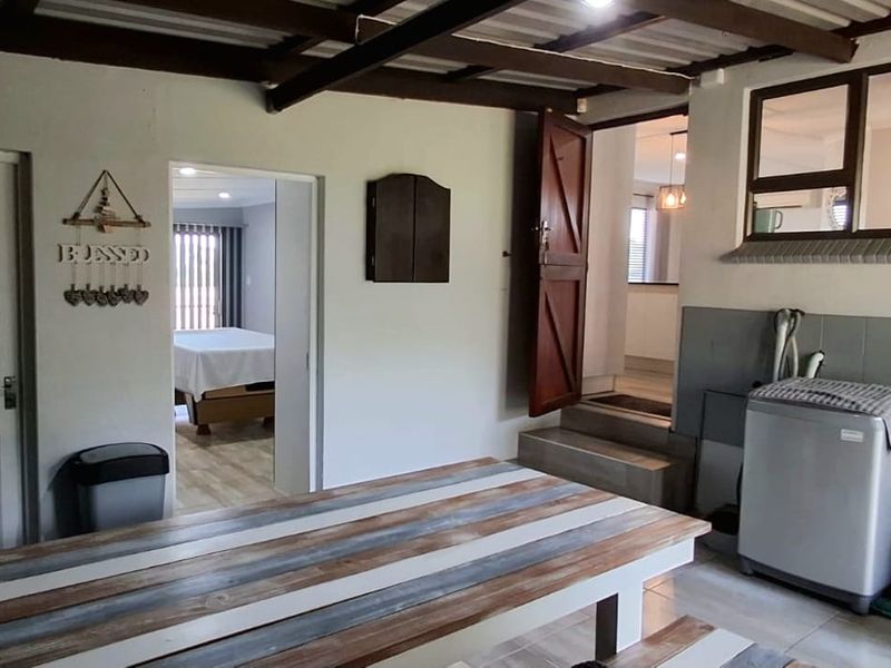 A utility space featuring exposed timber ceiling beams and tiled flooring, providing access to adjacent rooms with a stepped transition.