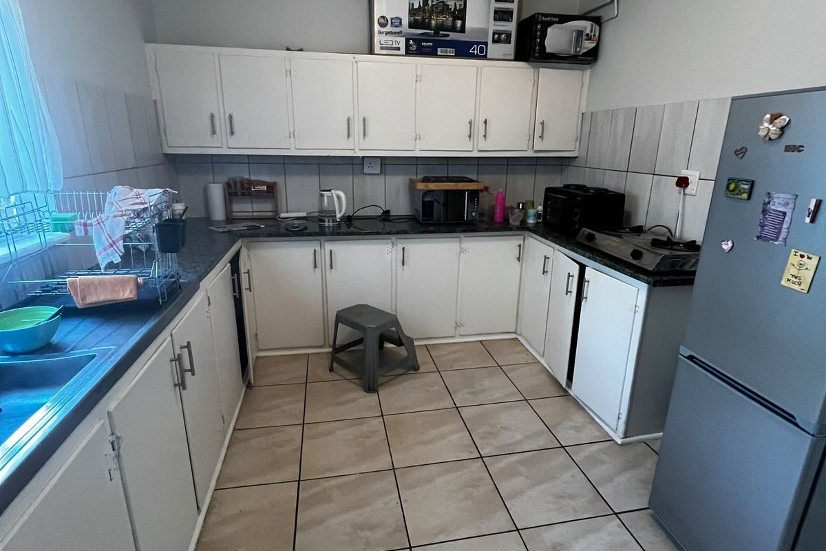 A functional kitchen featuring white cabinetry, tiled backsplash, and tiled flooring, offering a practical layout with ample storage and counter space.