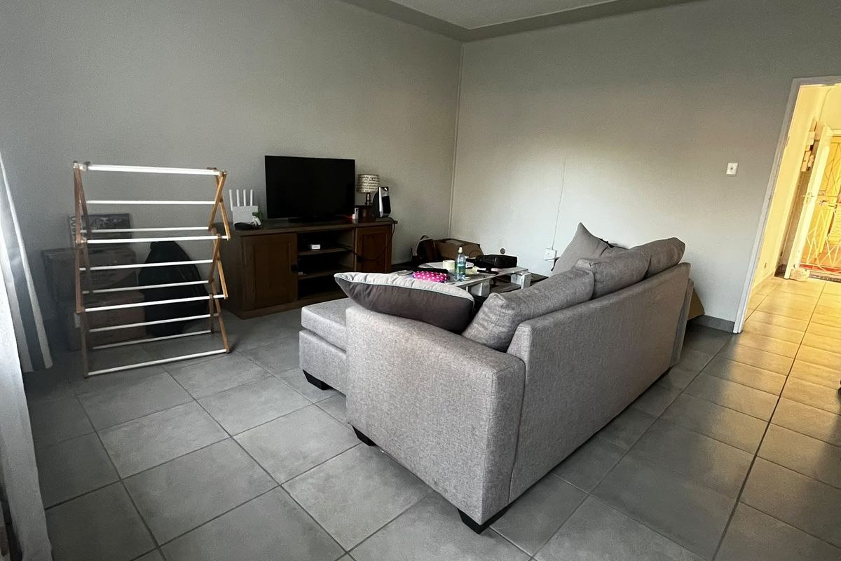 A living room area featuring neutral tiled flooring and a simple ceiling light fixture, providing a functional base for interior design.