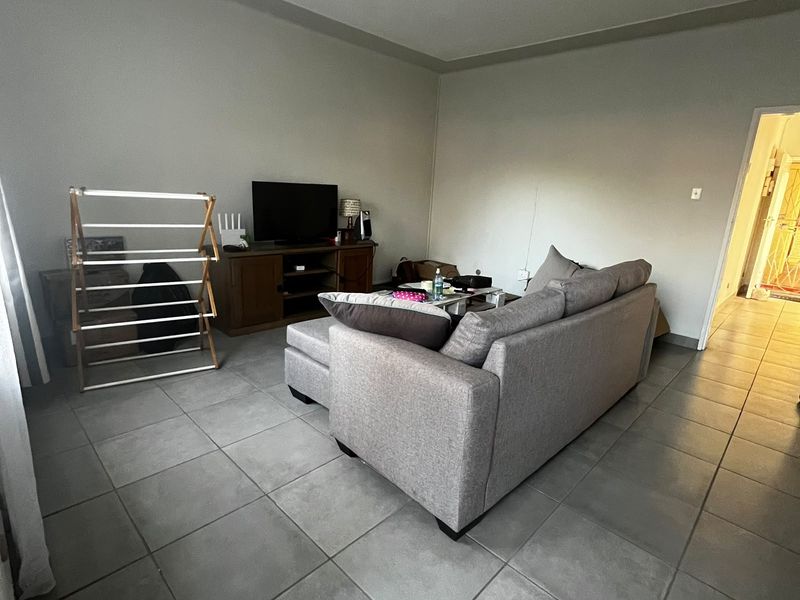 A living room area featuring neutral tiled flooring and a simple ceiling light fixture, providing a functional base for interior design.