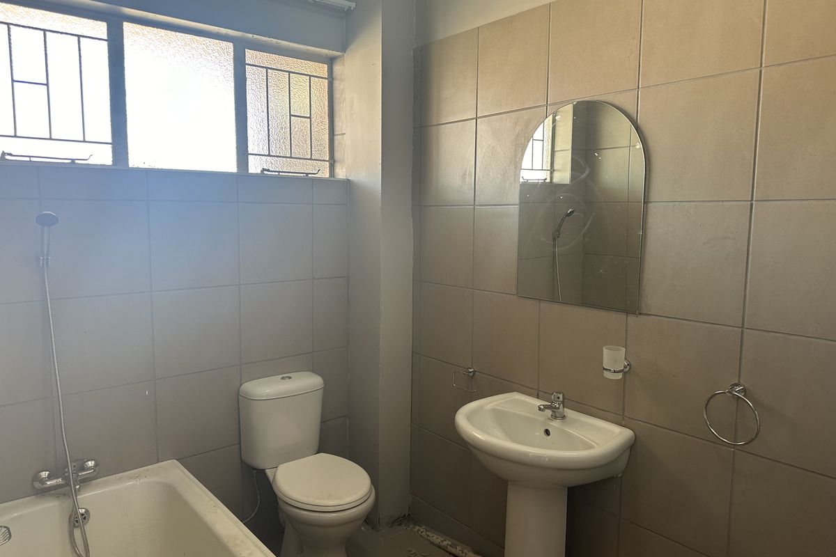 A functional bathroom featuring a pedestal basin, toilet, and bathtub with tiled walls. The space is ready for a modern renovation.