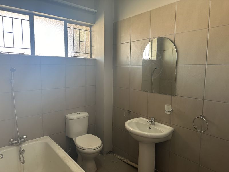 A functional bathroom featuring a pedestal basin, toilet, and bathtub with tiled walls. The space is ready for a modern renovation.