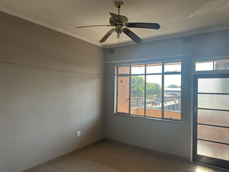 An empty bedroom featuring tiled flooring, a ceiling fan, and a glass panel door leading to an exterior balcony.