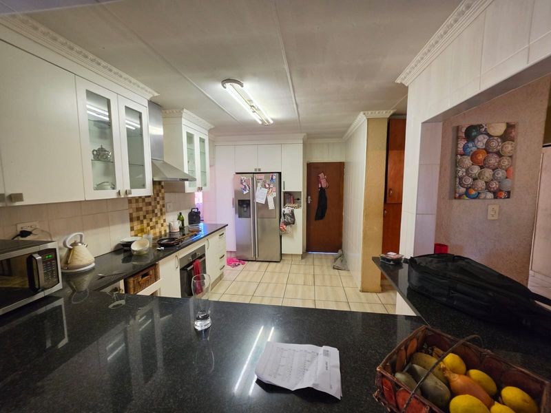 Functional kitchen featuring granite countertops, built-in oven, extractor fan, and ample cabinetry with glass-fronted display units and tiled flooring.