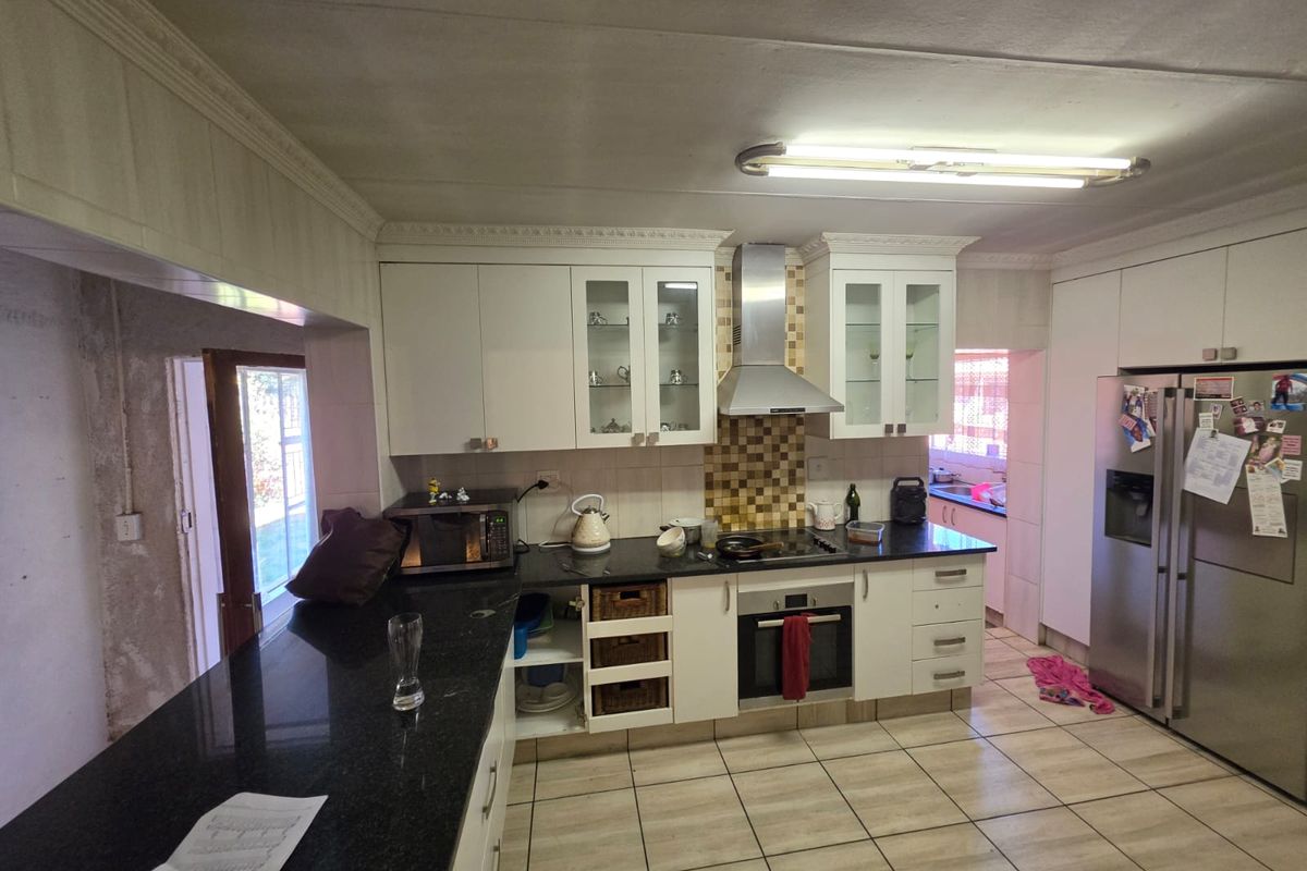 Kitchen featuring granite countertops, built-in oven, extractor fan, and tiled flooring. The space requires cosmetic updates and finishing to the wall area.