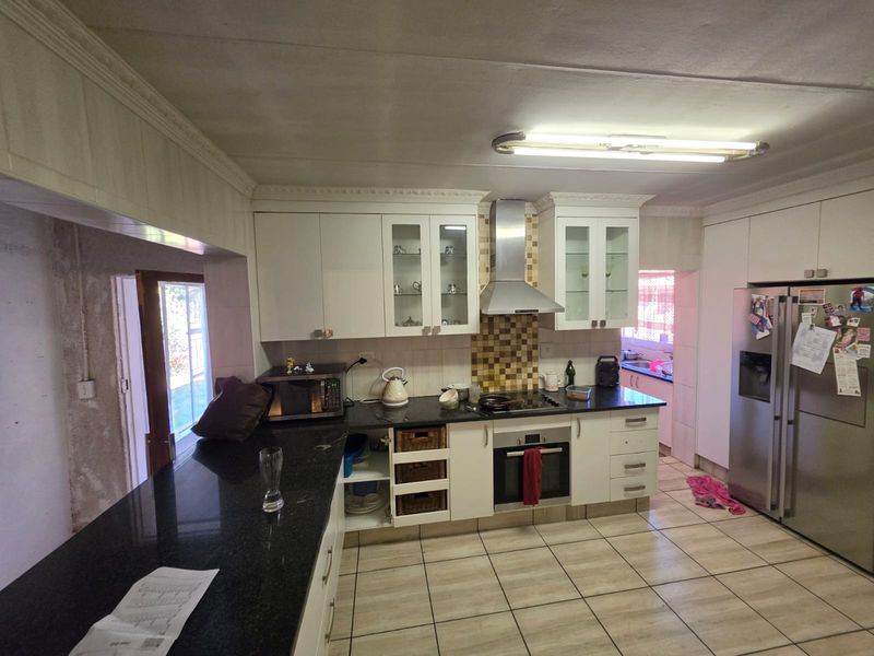 Kitchen featuring granite countertops, built-in oven, extractor fan, and tiled flooring. The space requires cosmetic updates and finishing to the wall area.