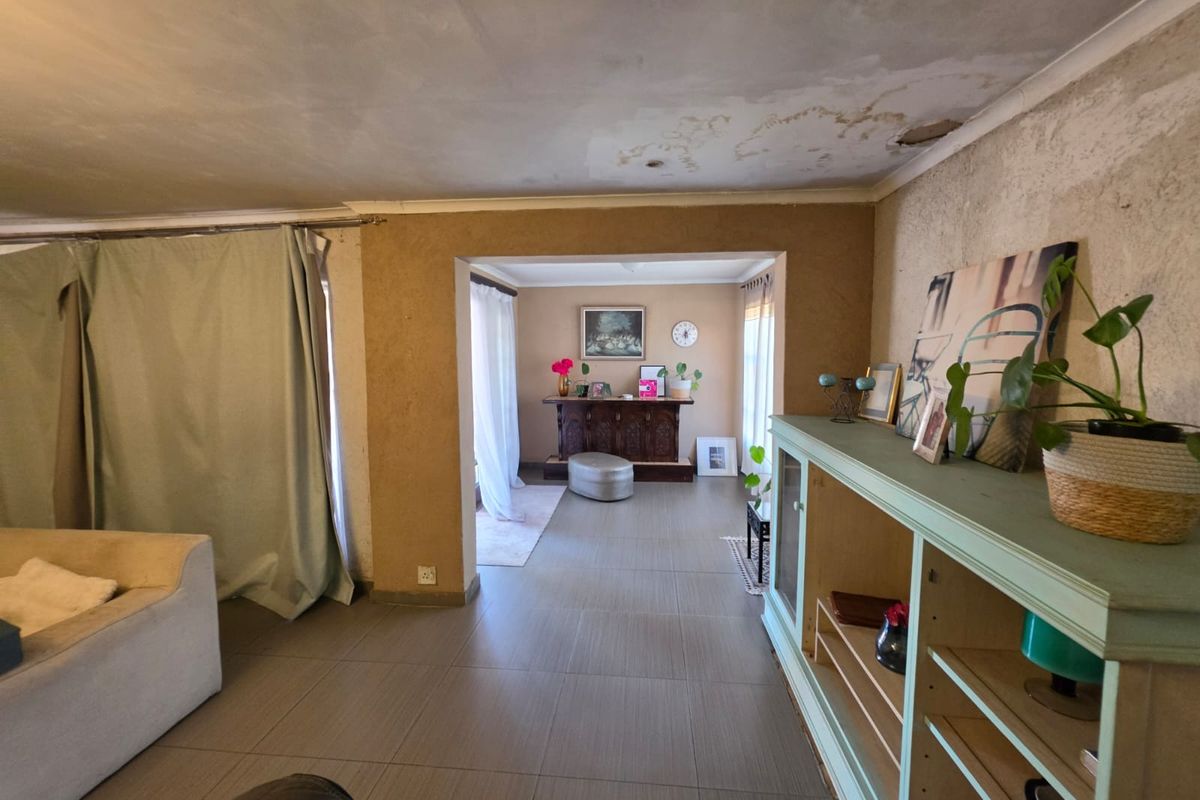 Living area featuring tiled flooring and open-plan layout, currently requiring significant ceiling and wall repairs to restore the space.