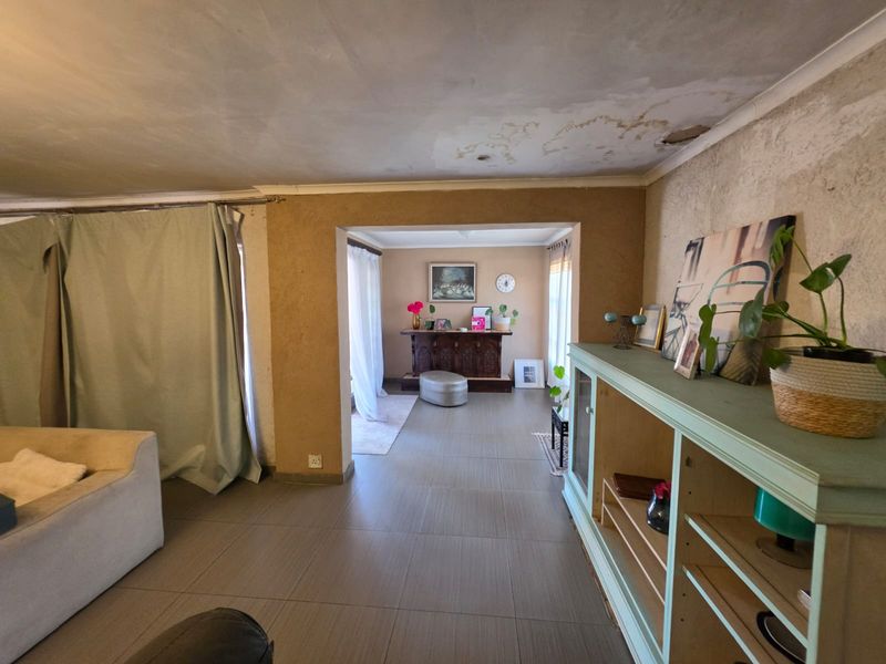 Living area featuring tiled flooring and open-plan layout, currently requiring significant ceiling and wall repairs to restore the space.