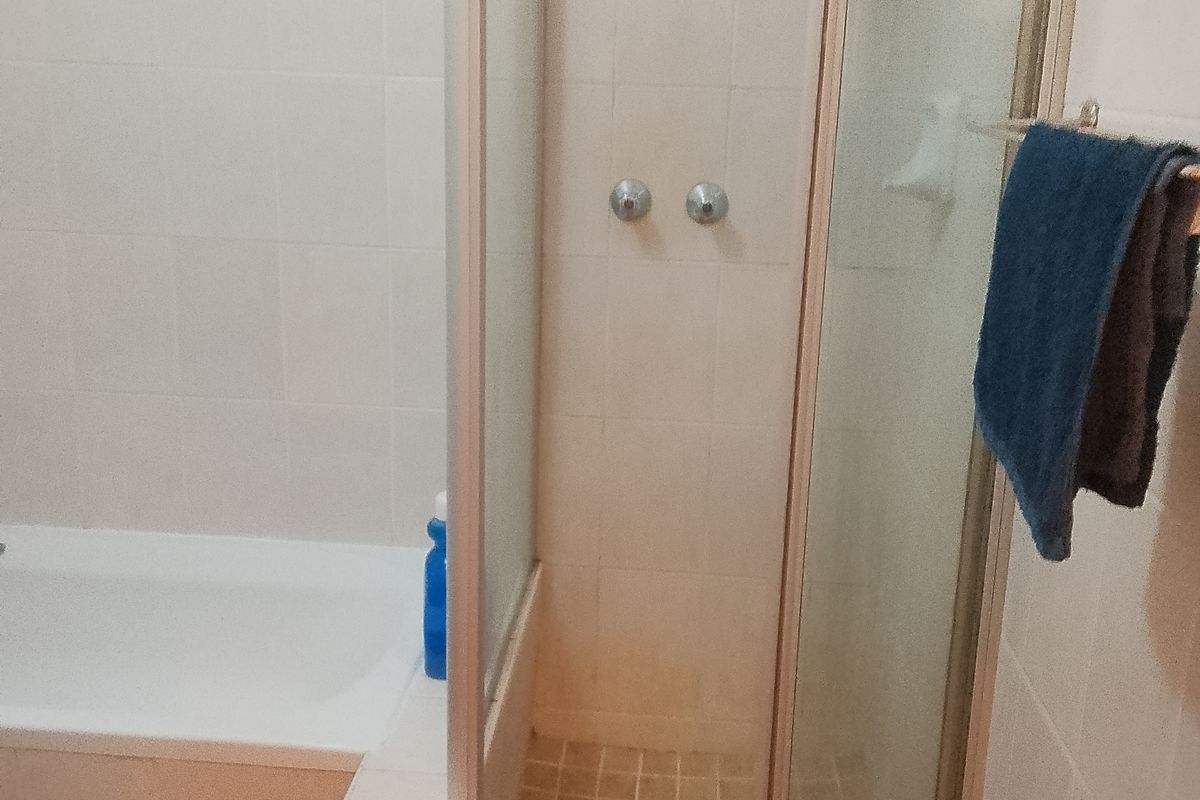 A functional bathroom featuring a built-in bathtub and a separate glass-enclosed shower with tiled finishes.