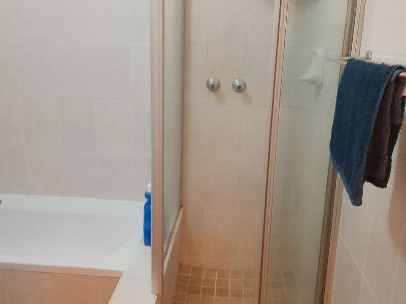 A functional bathroom featuring a built-in bathtub and a separate glass-enclosed shower with tiled finishes.