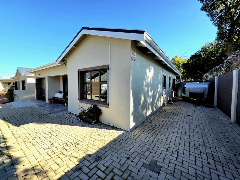 A well-maintained residential exterior featuring a paved driveway, secure perimeter fencing, and functional guttering systems.