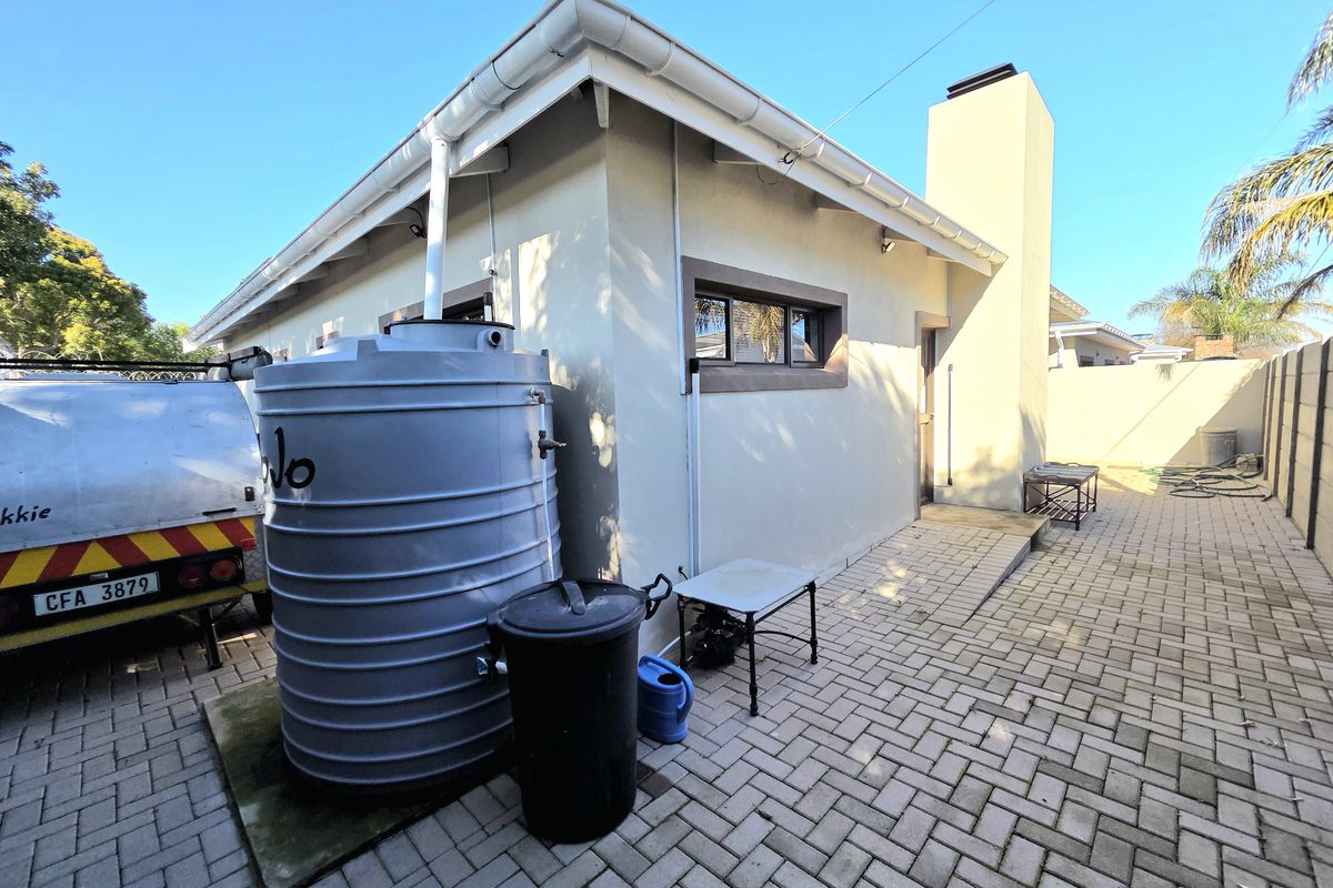 A paved rear courtyard area featuring a water storage tank, external chimney, and perimeter boundary wall.
