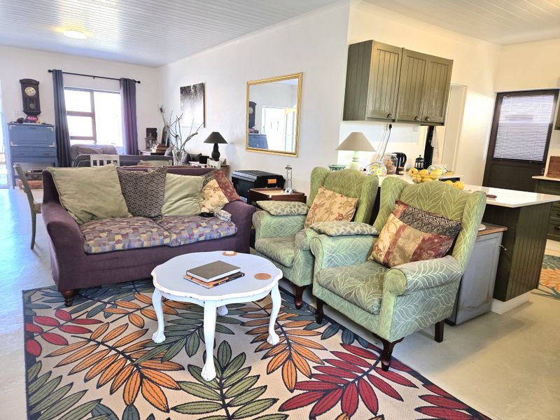 Open plan living area featuring a kitchen with green cabinetry and a central island, flowing into a comfortable lounge space.