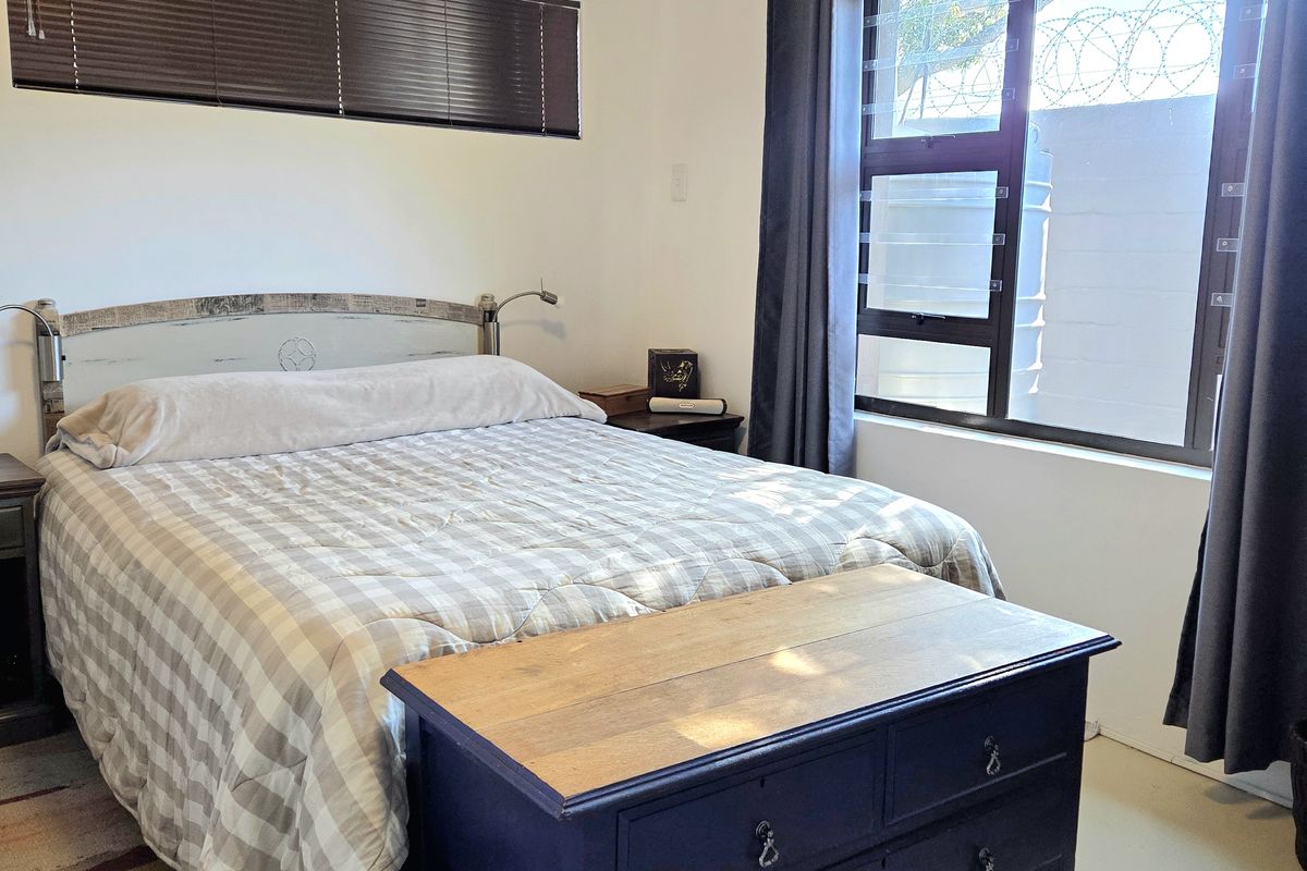 A bedroom featuring a tongue and groove ceiling, horizontal blinds, and a window with curtain rails.