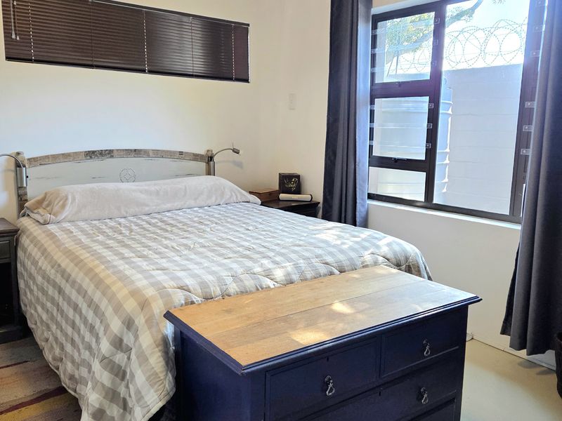A bedroom featuring a tongue and groove ceiling, horizontal blinds, and a window with curtain rails.