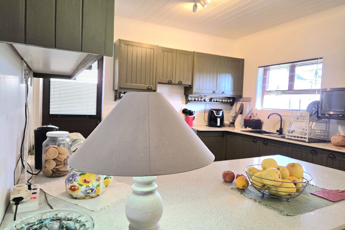 A functional kitchen featuring olive-toned cabinetry, a central island with a countertop, and a tongue and groove ceiling with track lighting.