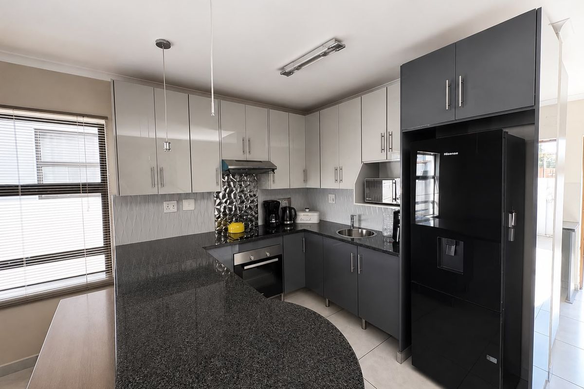 Modern kitchen featuring two-tone cabinetry, granite countertops, a tiled backsplash, and integrated appliances, offering a functional and contemporary cooking space.
