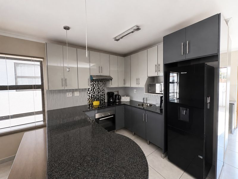 Modern kitchen featuring two-tone cabinetry, granite countertops, a tiled backsplash, and integrated appliances, offering a functional and contemporary cooking space.