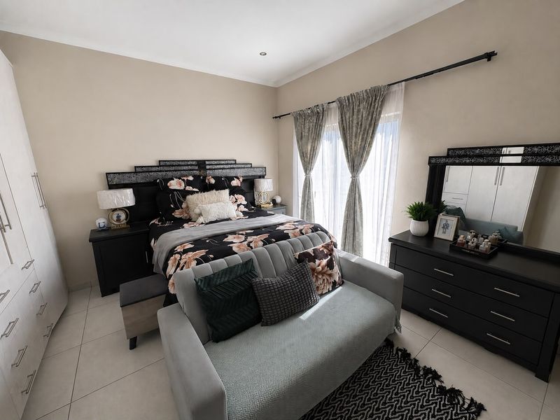 Spacious bedroom featuring tiled flooring, built-in cupboards, and a sliding door providing access to the exterior, finished with modern recessed lighting.