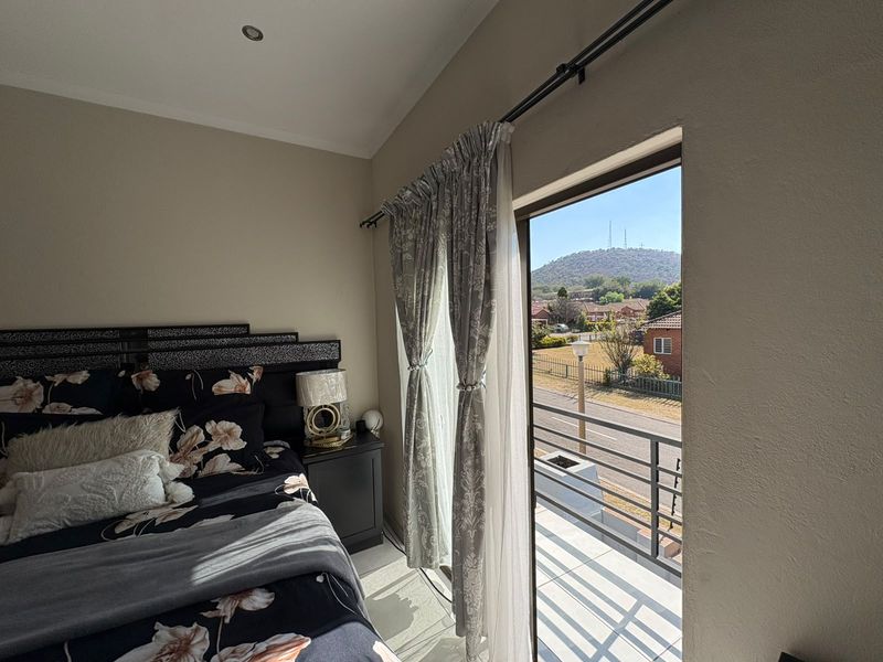 A well-lit bedroom featuring direct access to a private balcony with scenic views, neutral wall finishes, and recessed ceiling lighting.