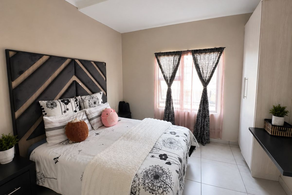 A well-maintained bedroom featuring neutral wall tones, tiled flooring, and a functional built-in wardrobe.