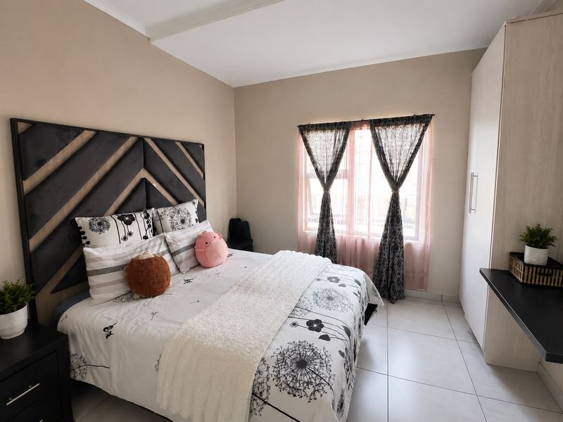 A well-maintained bedroom featuring neutral wall tones, tiled flooring, and a functional built-in wardrobe.