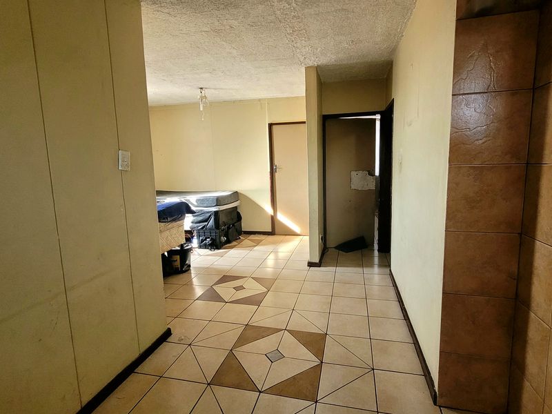 A tiled hallway area showing signs of wear, leading into adjacent rooms with visible wall and ceiling finish deterioration.