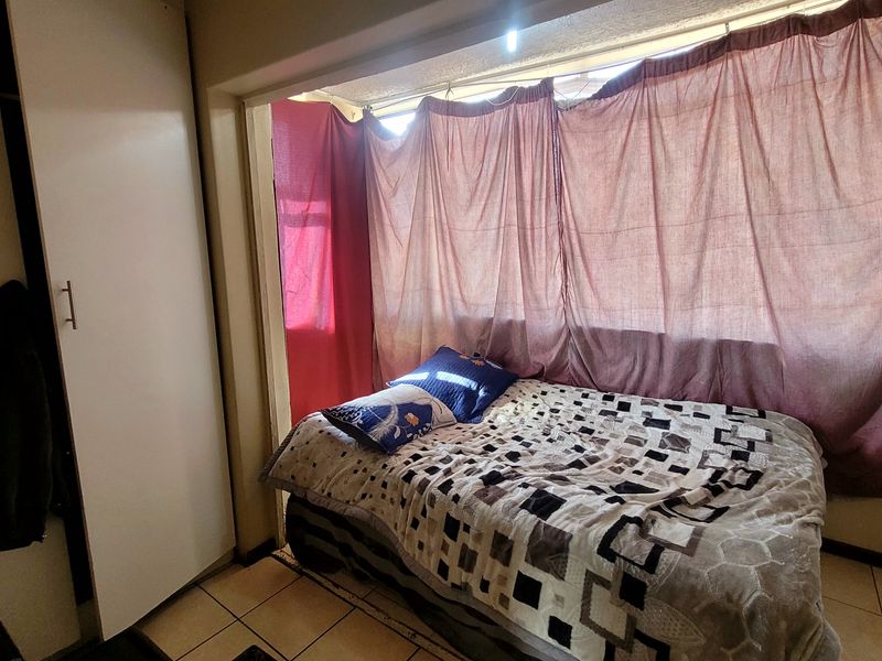A bedroom featuring tiled flooring and a built-in wardrobe, offering a functional space with natural light.