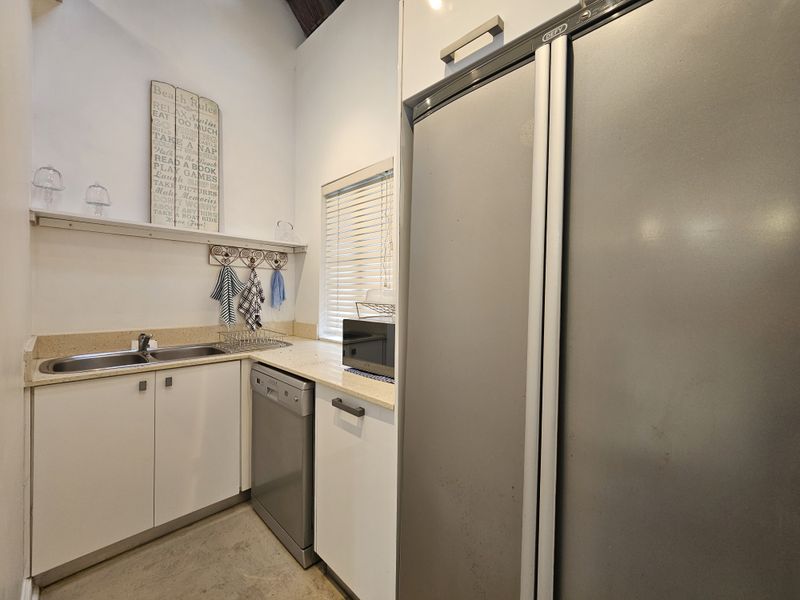 A functional scullery area featuring built-in cabinetry, a double bowl sink, integrated dishwasher, and ample counter space for food preparation and cleaning.