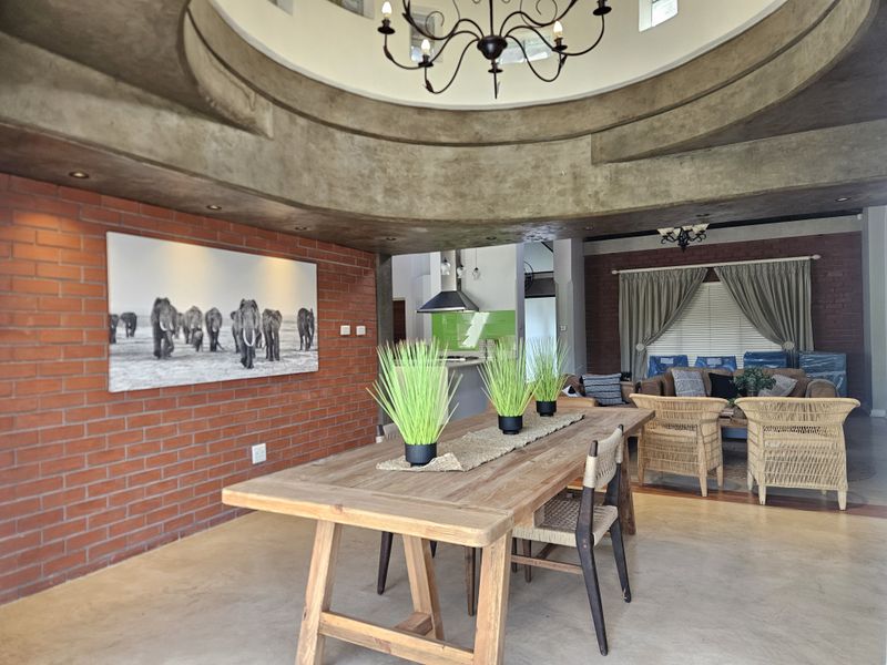 Spacious open-plan living and dining area featuring a striking architectural ceiling dome, exposed brick feature walls, and polished concrete flooring.