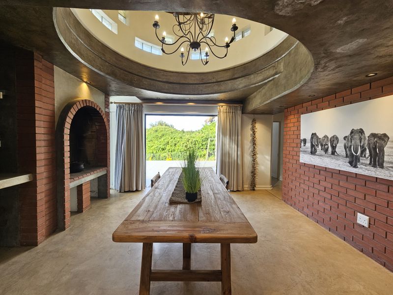 Spacious dining area featuring exposed brick walls, a unique domed ceiling with a chandelier, polished concrete floors, and a built-in brick fireplace.