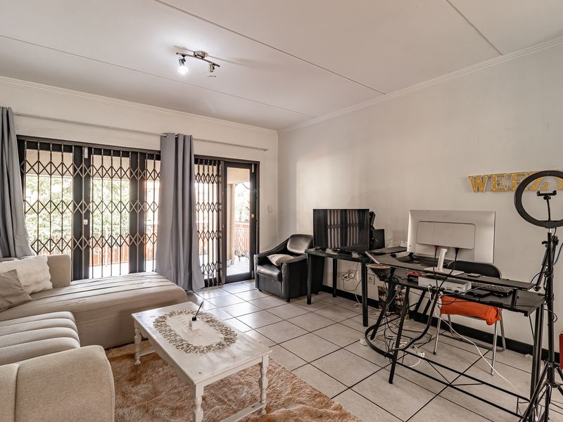A living room featuring ceramic floor tiles and sliding glass doors with security gates, providing access to an outdoor area.