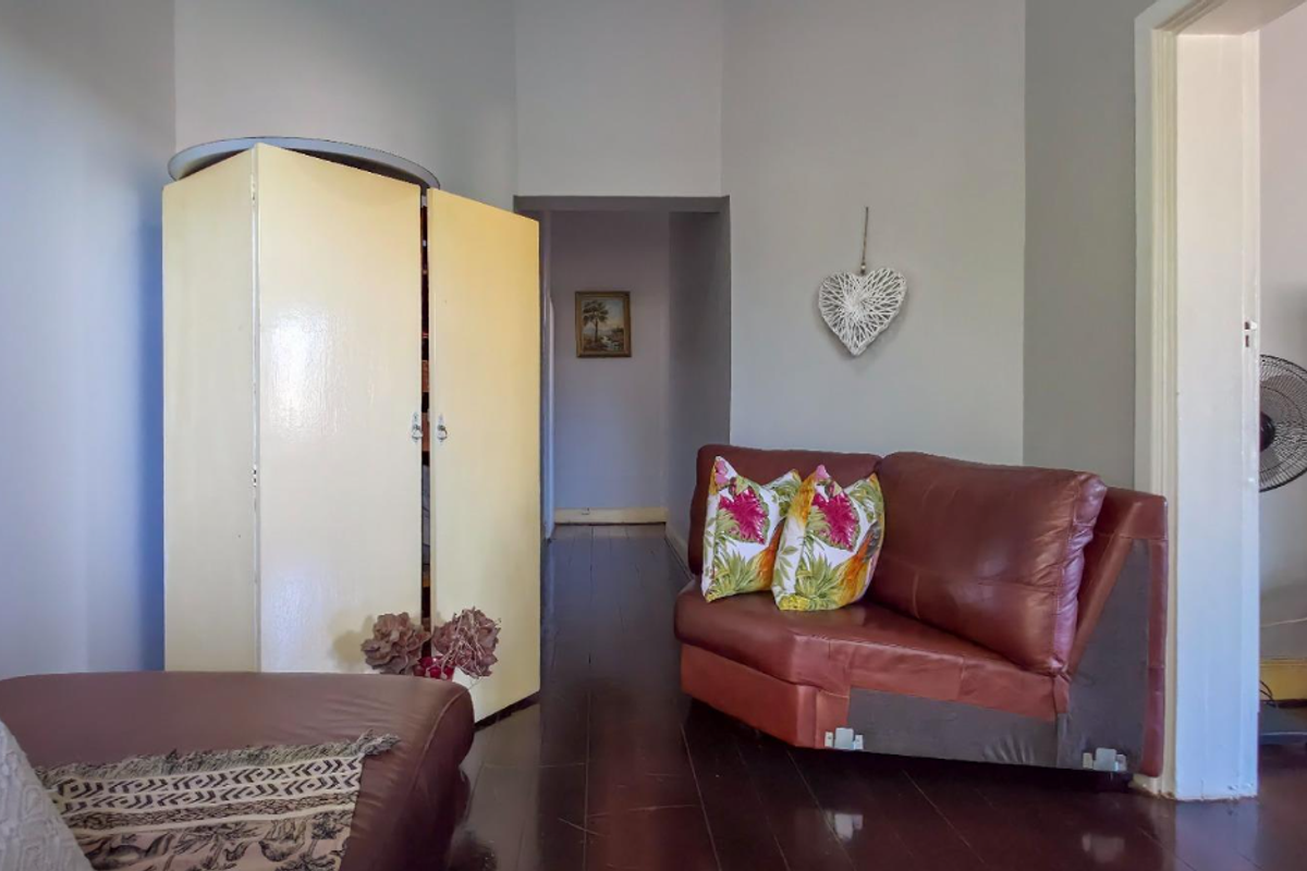 A living area featuring polished timber flooring and an open archway leading to a hallway.